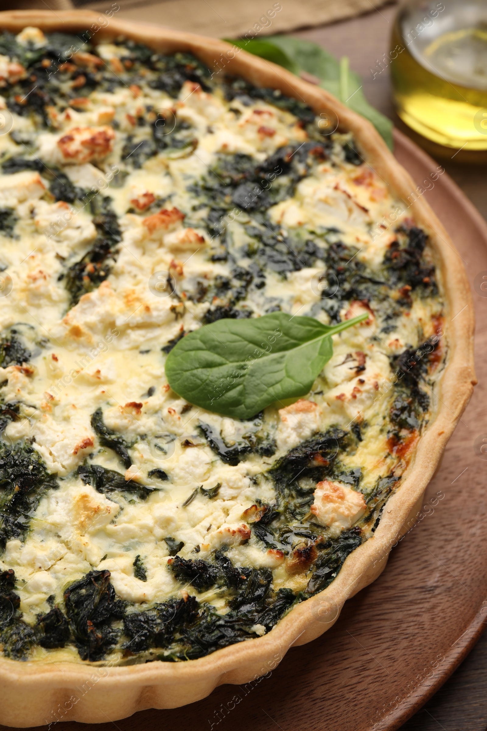 Photo of Delicious homemade spinach quiche on wooden board, closeup