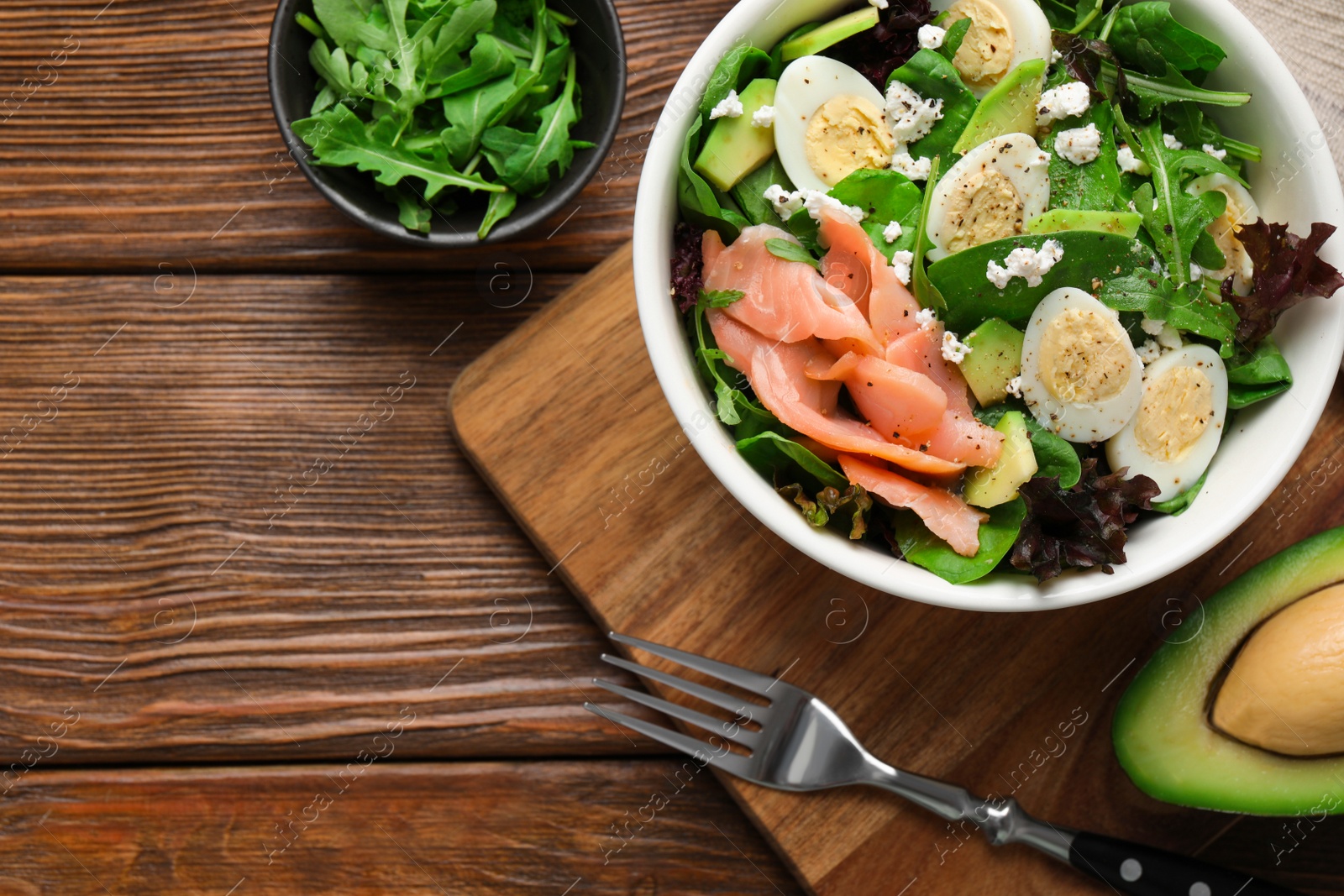 Photo of Delicious salad with boiled eggs, salmon and cheese served on wooden table, flat lay. Space for text