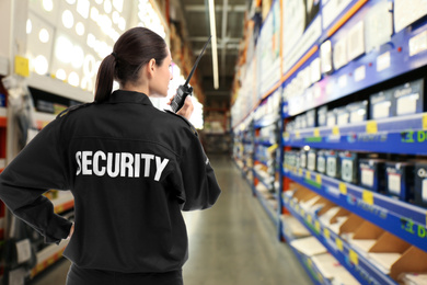 Security guard using portable radio transmitter in shopping mall, space for text