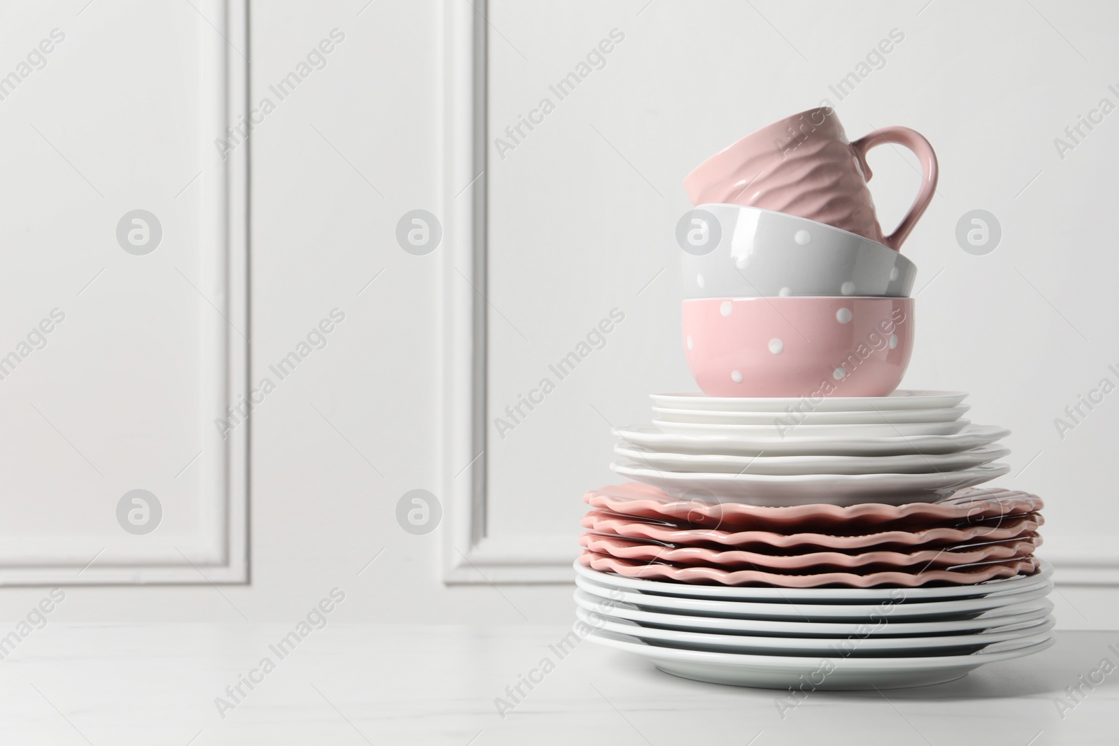 Photo of Beautiful ceramic dishware and cup on white marble table, space for text