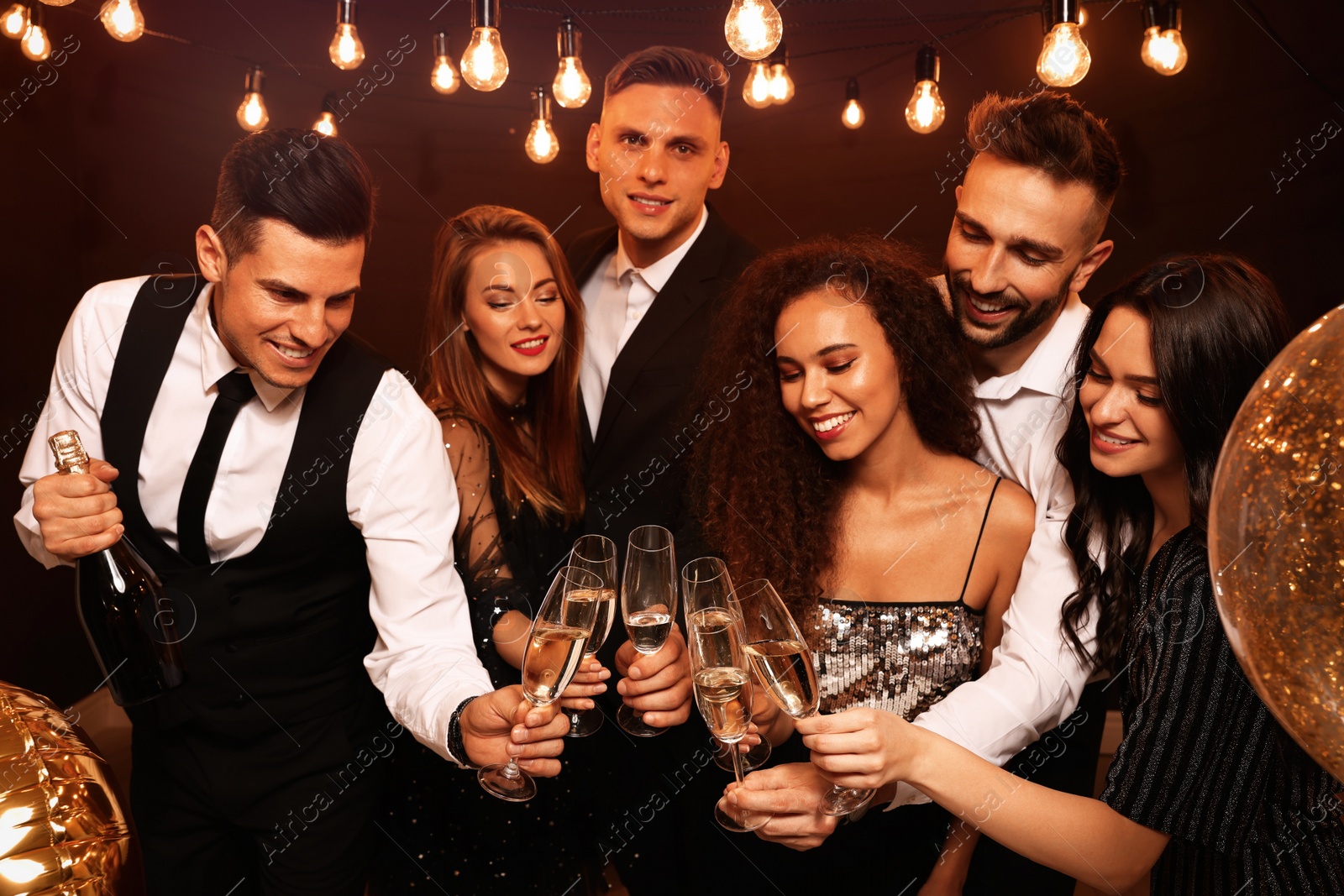 Photo of Happy friends with glasses of sparkling wine celebrating New Year indoors