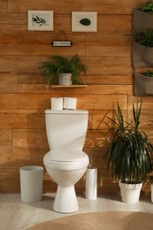 Photo of Stylish bathroom interior with toilet bowl and green plants
