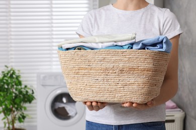 Woman with basket full of laundry in bathroom, closeup
