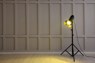 Photo of Bright yellow spotlight near wall indoors, space for text