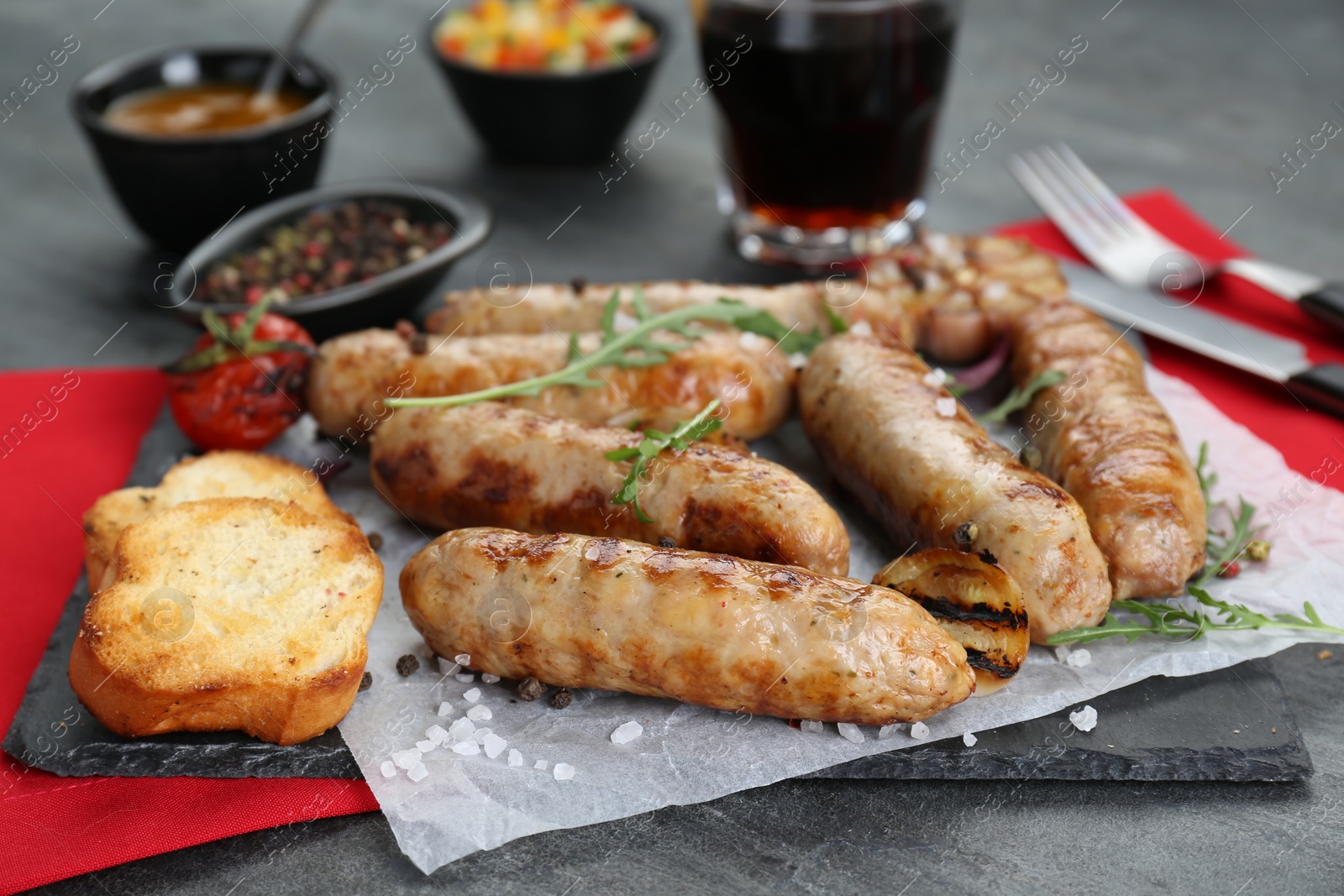 Photo of Tasty fresh grilled sausages with vegetables on grey table, closeup