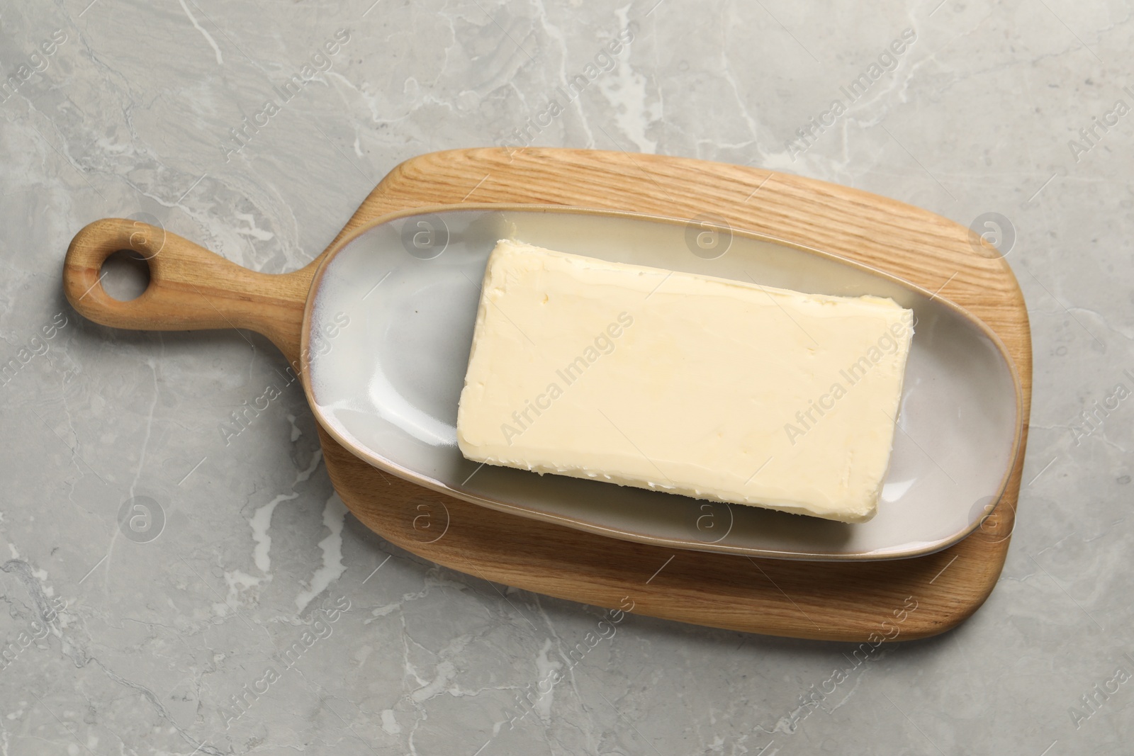 Photo of Block of tasty butter on grey table, top view