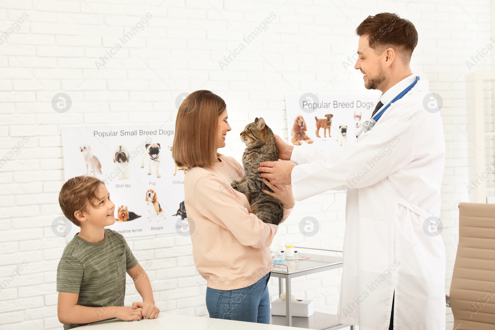 Photo of Son and mother with their pet visiting veterinarian in clinic