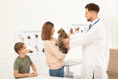 Photo of Son and mother with their pet visiting veterinarian in clinic