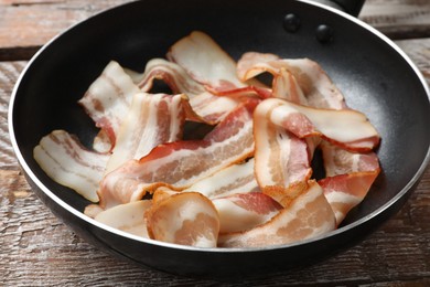 Photo of Delicious bacon slices in frying pan on wooden table, closeup