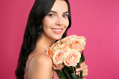 Portrait of smiling woman with beautiful bouquet on pink background