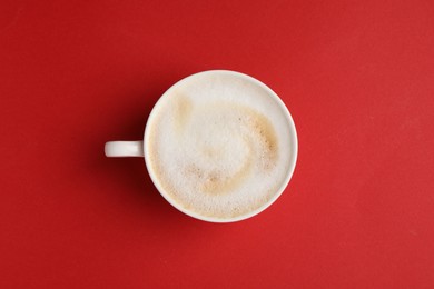 Photo of Tasty cappuccino in coffee cup on red background, top view