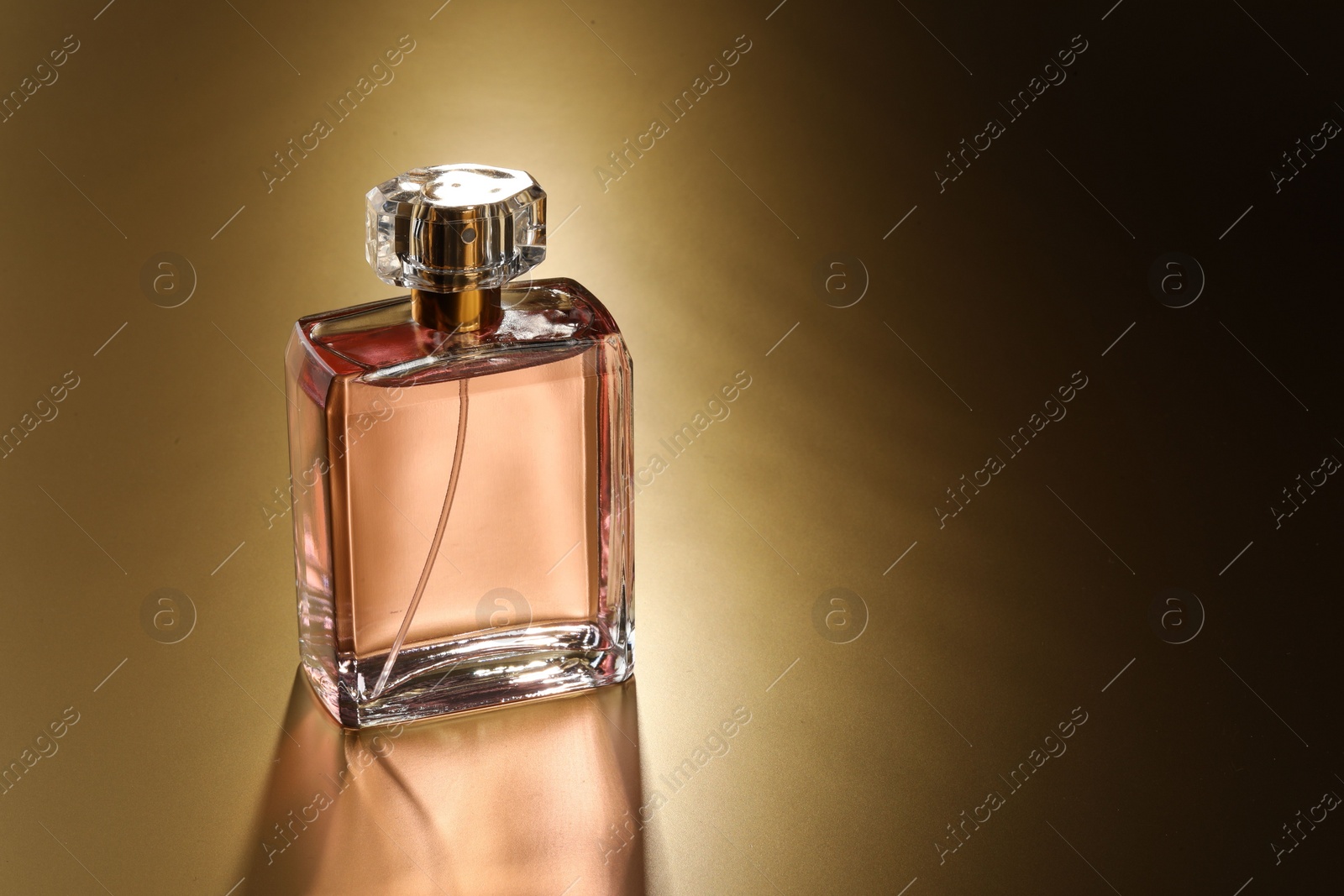 Photo of Luxury women's perfume. Sunlit glass bottle on golden background, space for text