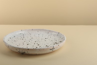 Photo of Beautiful ceramic plate on pale yellow table, closeup. Space for text