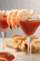 Photo of Tasty shrimp cocktail with sauce in glasses on light wooden table, closeup