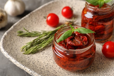Photo of Jar with sun dried tomatoes on plate, closeup