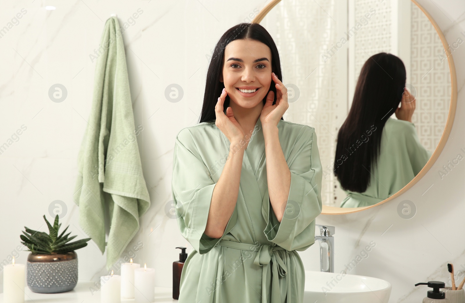 Photo of Beautiful young woman near mirror in bathroom