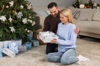 Photo of Happy couple with Christmas gift at home