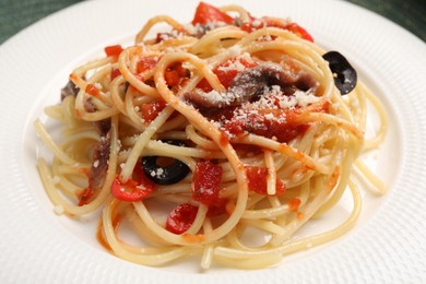 Delicious pasta with anchovies, tomatoes and parmesan cheese on plate, closeup