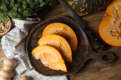 Cut fresh ripe pumpkin on wooden table, flat lay