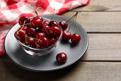 Photo of Wet red cherries on wooden table, space for text