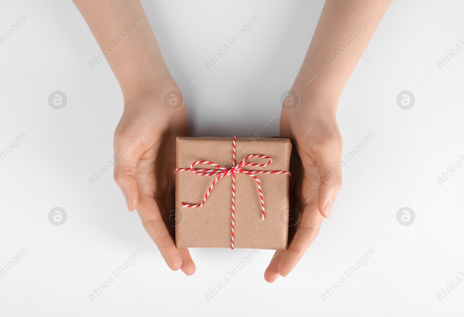 Photo of Woman holding parcel wrapped in kraft paper on white background, top view