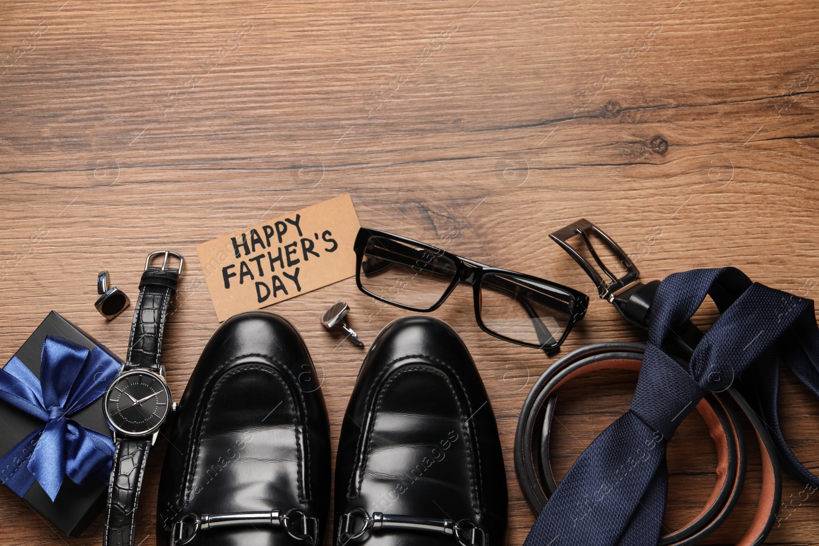 Photo of Card with phrase Happy Father's Day, shoes, gift box and different men accessories on wooden background, flat lay. Space for text