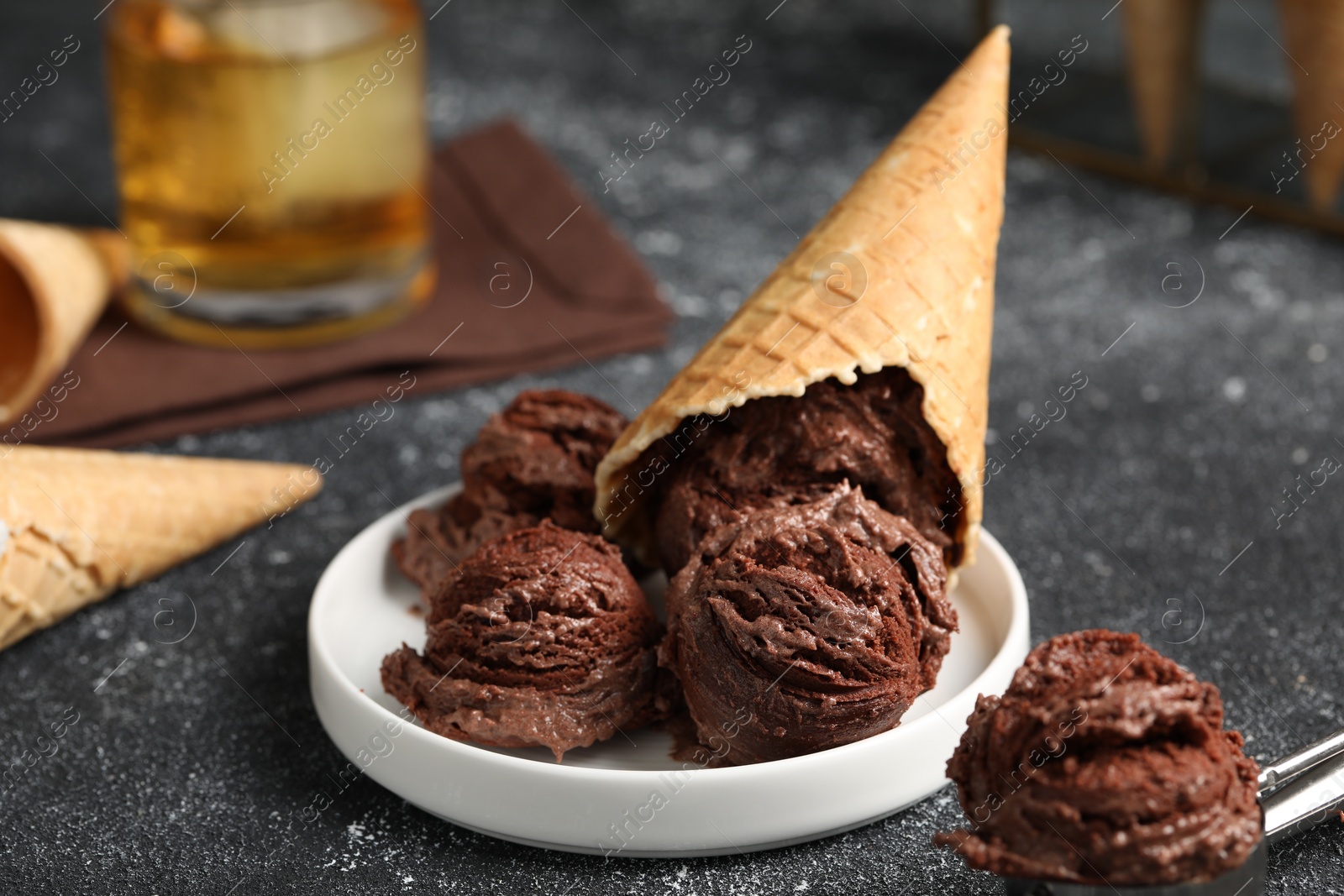 Photo of Tasty ice cream scoops and waffle cones on dark textured table, closeup