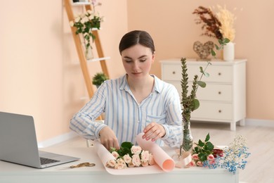 Photo of Woman making bouquet following online florist course at home. Time for hobby