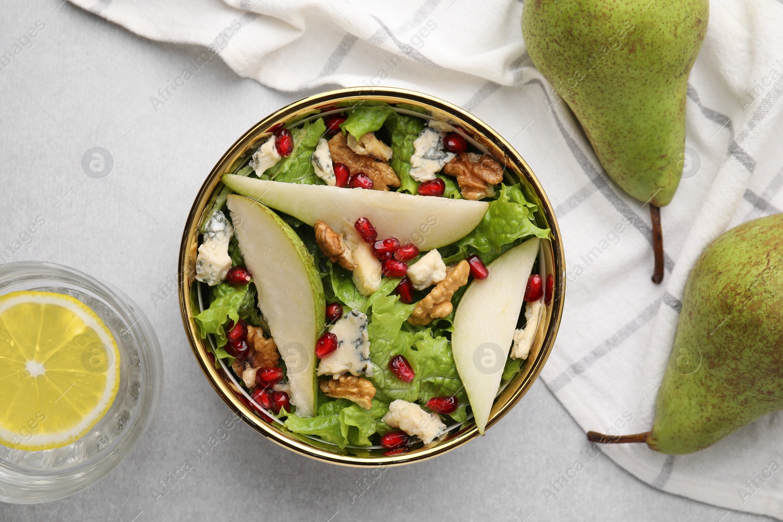 Photo of Delicious pear salad in bowl, water with lemon and fruits on light table, flat lay