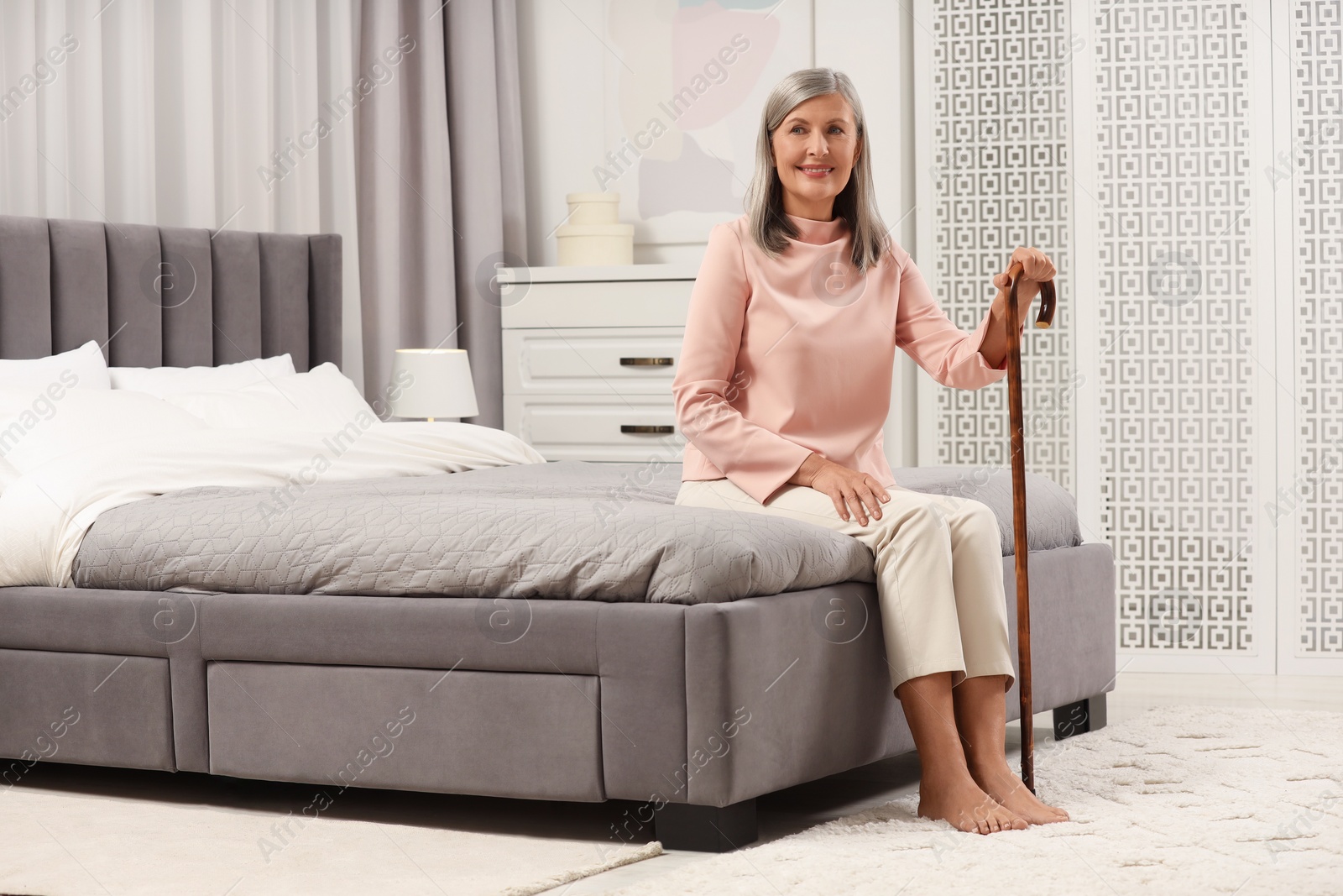 Photo of Mature woman with walking cane on bed at home