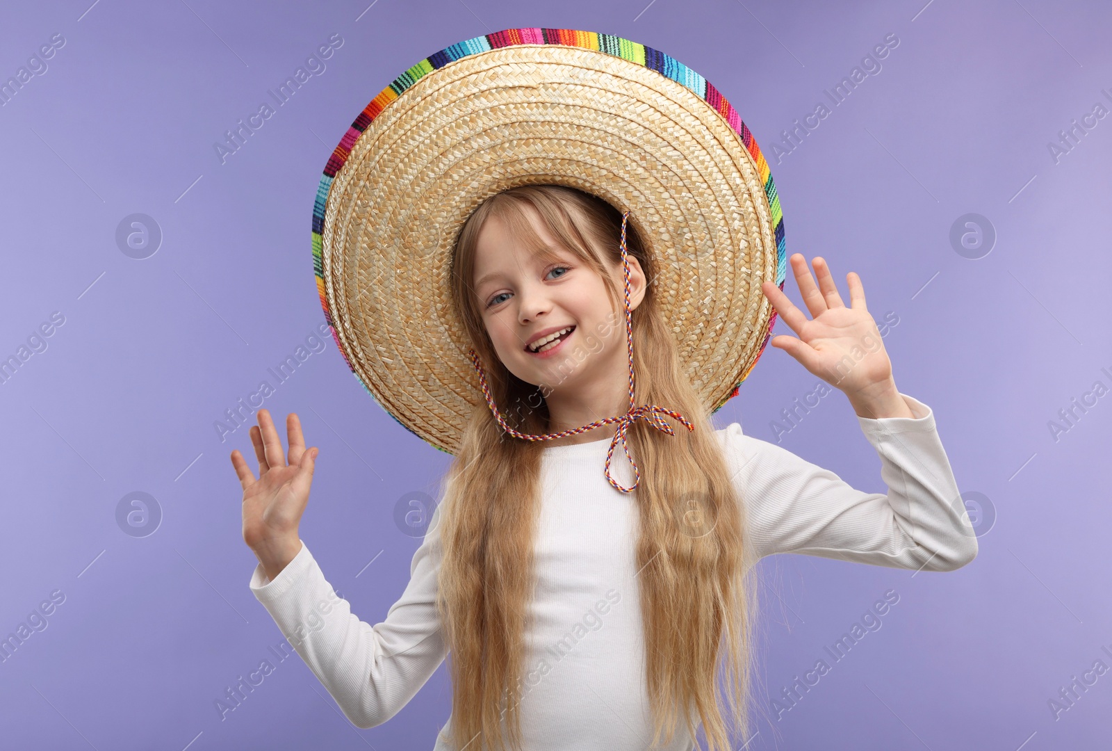 Photo of Cute girl in Mexican sombrero hat on purple background