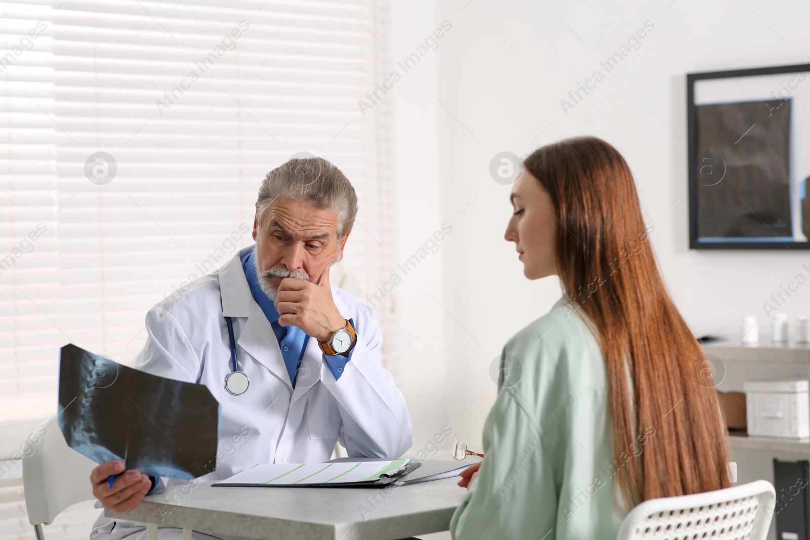 Photo of Orthopedist showing X-ray picture to patient in clinic