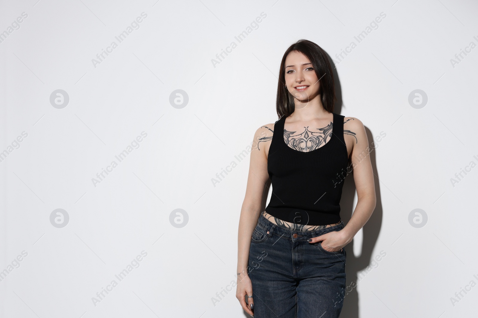 Photo of Portrait of smiling tattooed woman on light background. Space for text