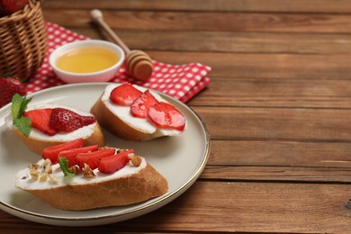 Delicious bruschettas with ricotta cheese, walnuts, mint, strawberries and honey on wooden table, closeup. Space for text