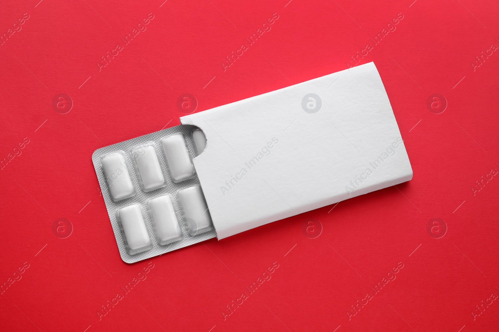 Photo of Blister with chewing gums on red background, top view