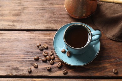 Photo of Turkish coffee. Freshly brewed beverage and beans on wooden table, above view. Space for text