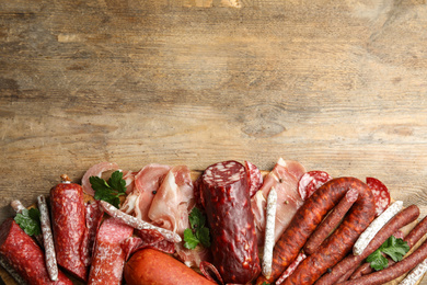 Photo of Different types of sausages with parsley on wooden table, top view. Space for text