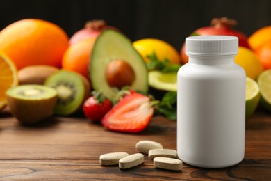 Photo of Vitamin pills, bottle and fresh fruits on wooden table. Space for text