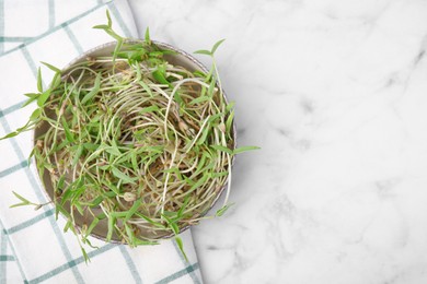 Photo of Mung bean sprouts in bowl with kitchen towel on white marble table, top view. Space for text