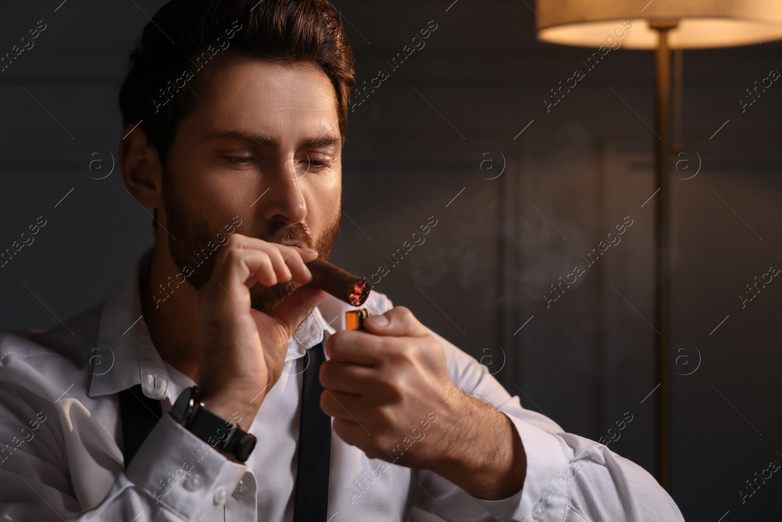 Photo of Handsome man lightning cigar at home. Space for text