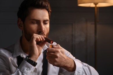 Photo of Handsome man lightning cigar at home. Space for text