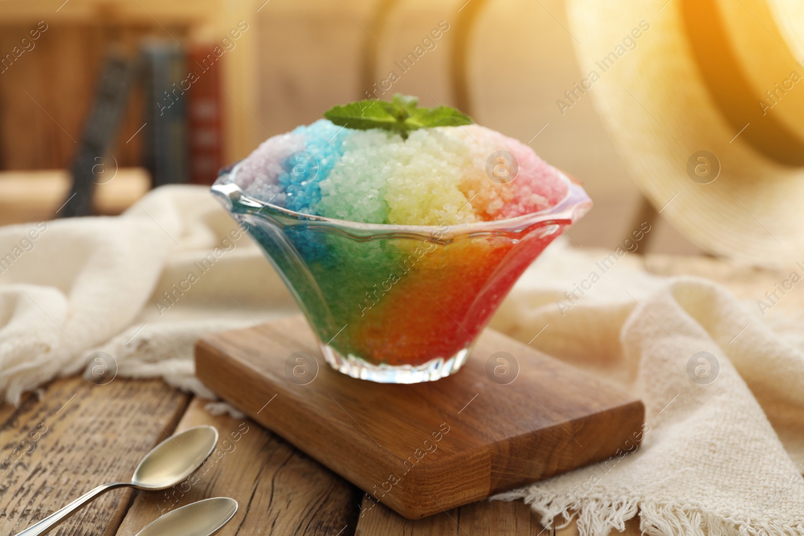 Photo of Rainbow shaving ice in glass dessert bowl on wooden  table indoors