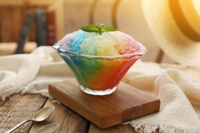 Photo of Rainbow shaving ice in glass dessert bowl on wooden  table indoors