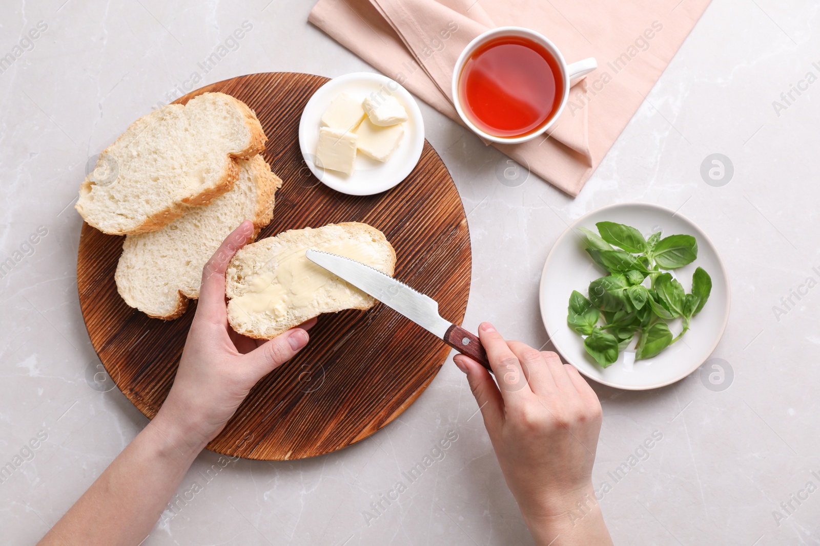 Photo of Woman spreading butter on slice of bread over table, closeup