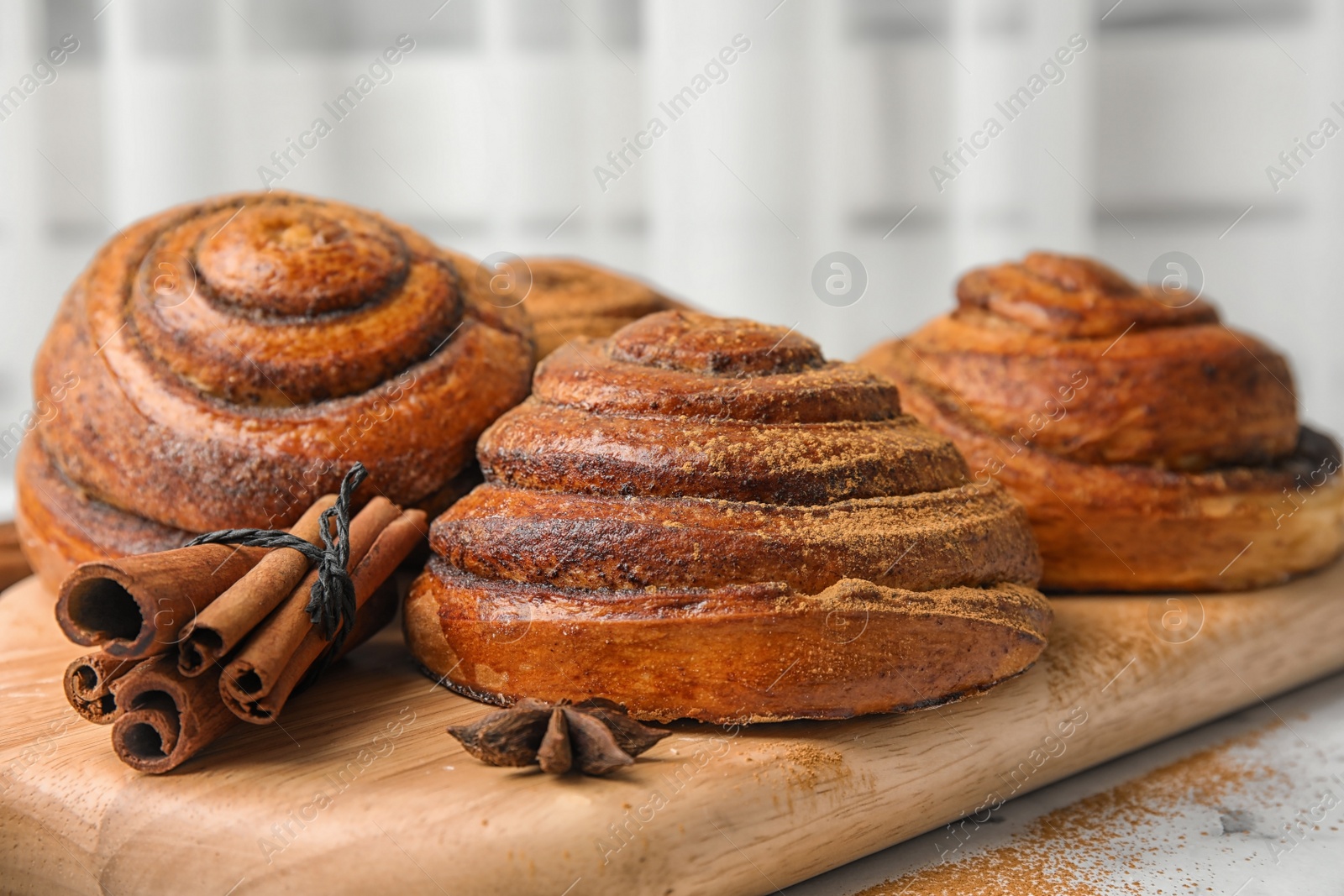 Photo of Wooden board with cinnamon rolls on table, closeup