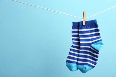 Photo of Small socks hanging on washing line against color background, space for text. Baby accessories