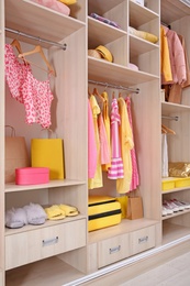 Photo of Stylish clothes, shoes and accessories in large wardrobe closet