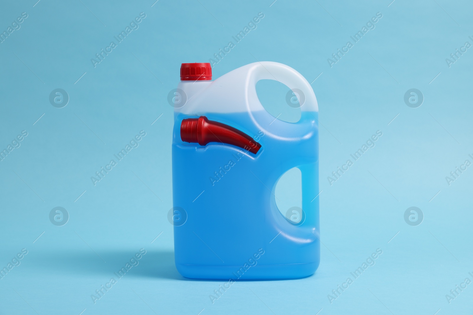 Photo of Plastic canister with color liquid on light blue background