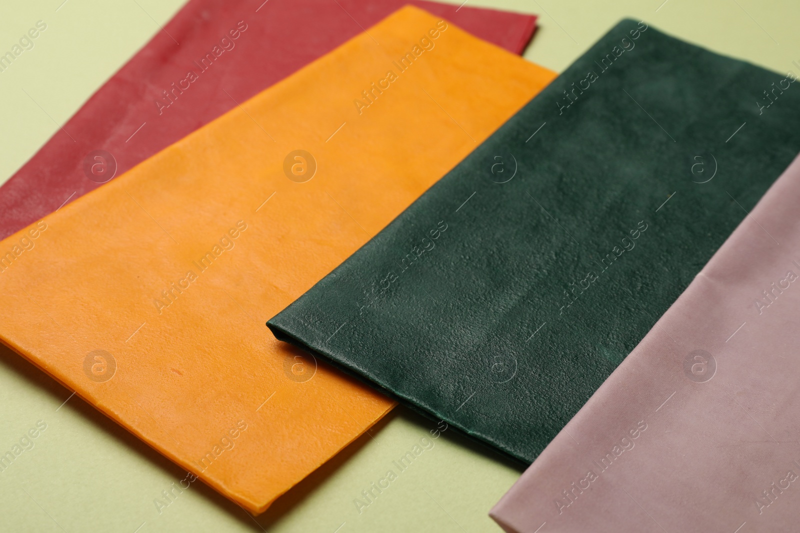 Photo of Different beeswax food wraps on light green background, closeup