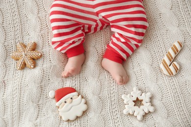 Photo of Cute little baby and Christmas cookies on blanket, top view
